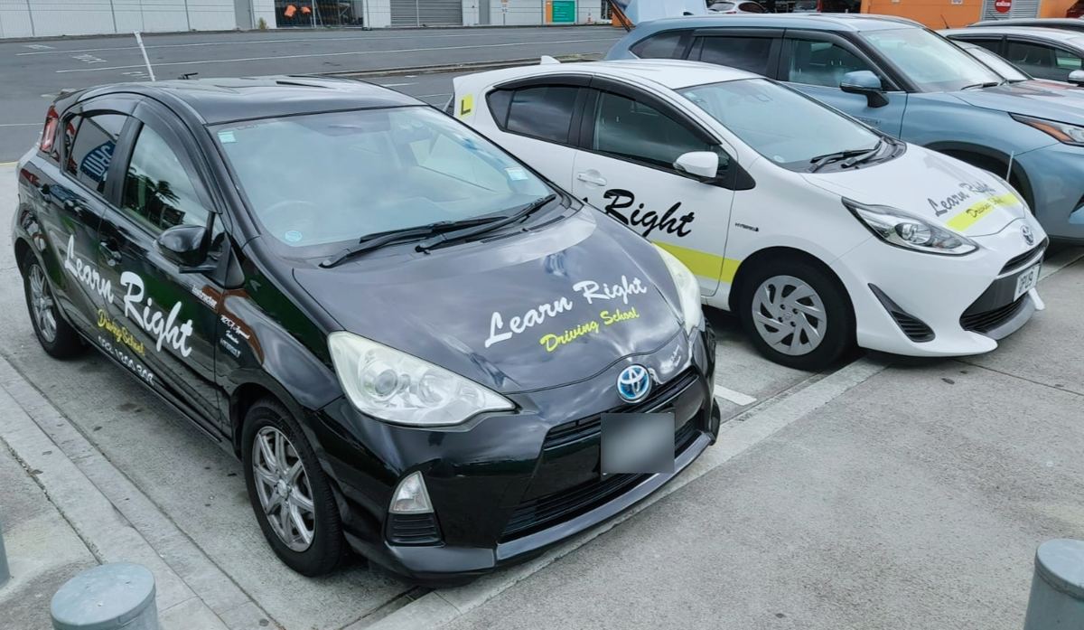 Two Learn Right Driving School training cars, one black and one white, parked side by side